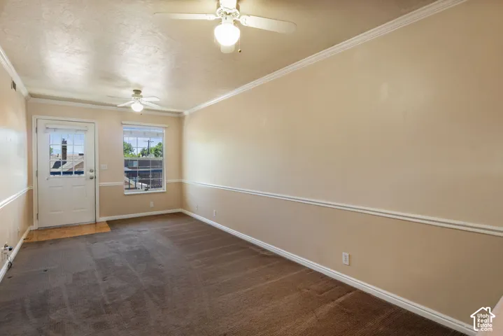 Spacious room featuring neutral paint, crown molding, chair rail molding, two ceiling fans, and a glass-paneled exterior door
