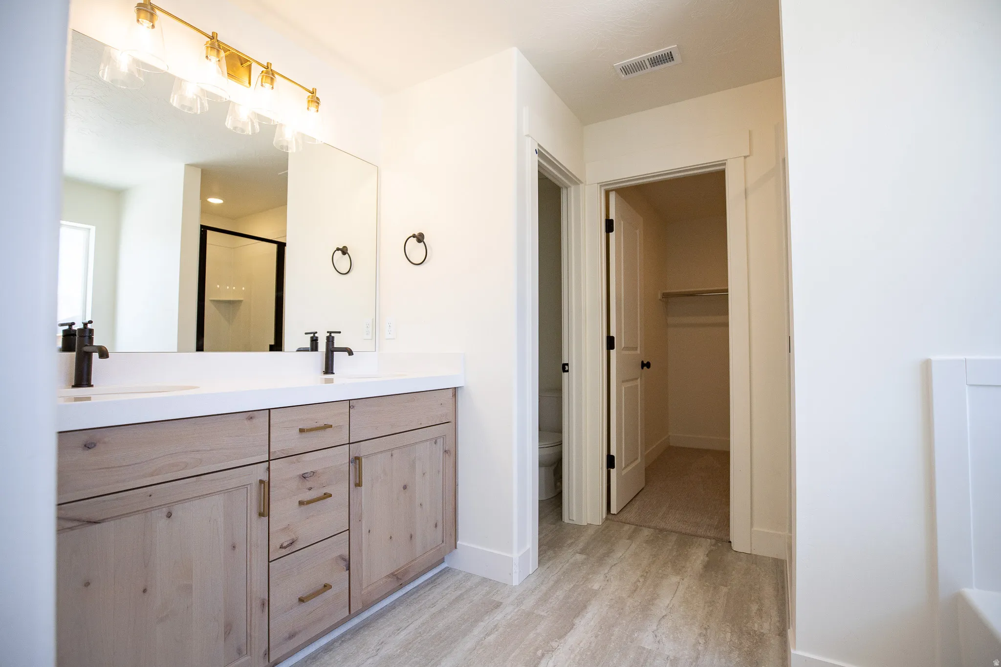Terrific primary bath with dual sinks, quartz slab countertops, stained wood cabinets, soaking tub and walk-in shower.