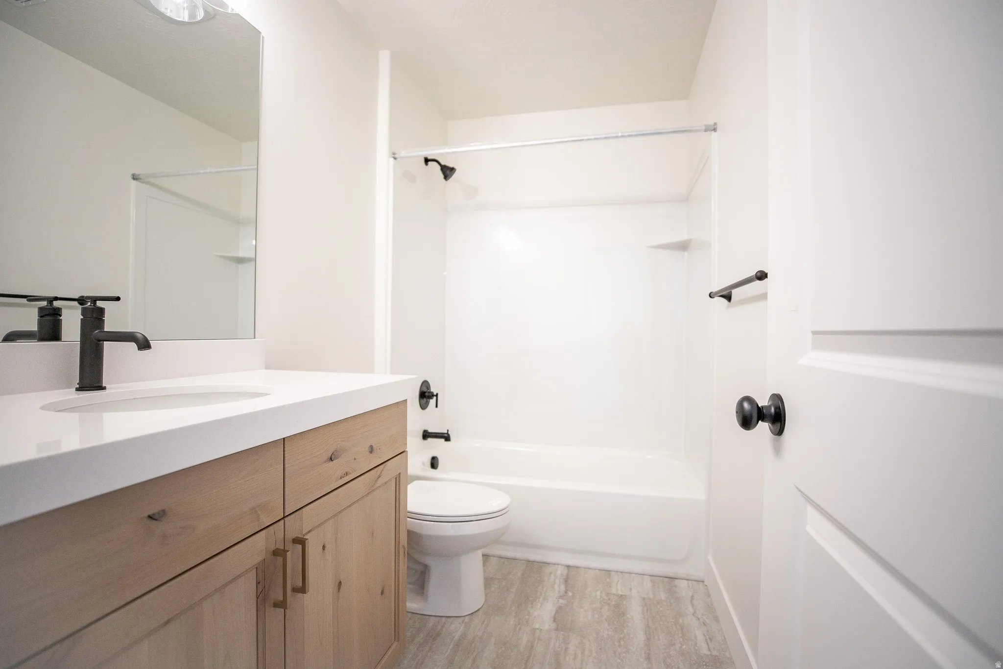 Full secondary bath with quartz slab countertops and stained wood cabinets.