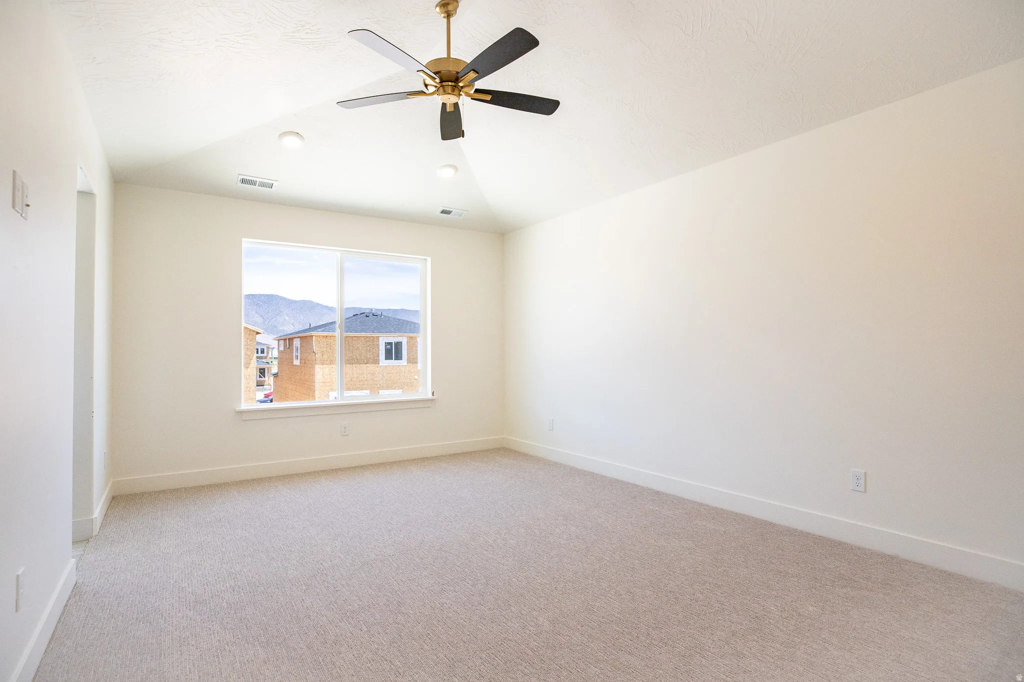 Spacious primary bedroom with vaulted ceiling and ceiling fan.