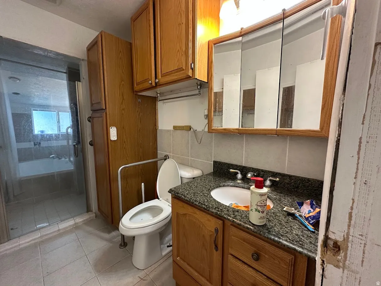 Bathroom featuring a single vanity with granite-style countertop, wood-finish cabinetry, and a mirrored medicine cabinet