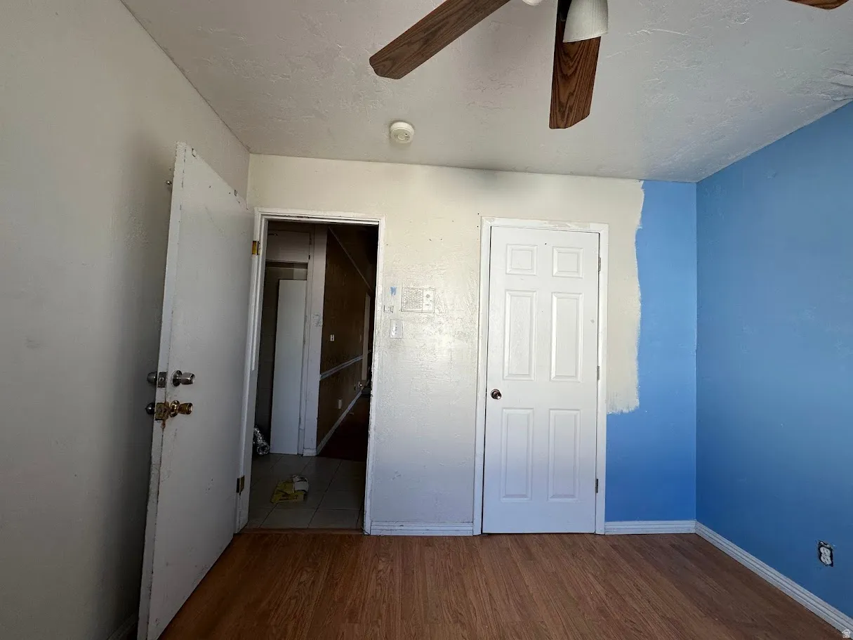 Room featuring wood-finish flooring, two panel doors, and a ceiling fan