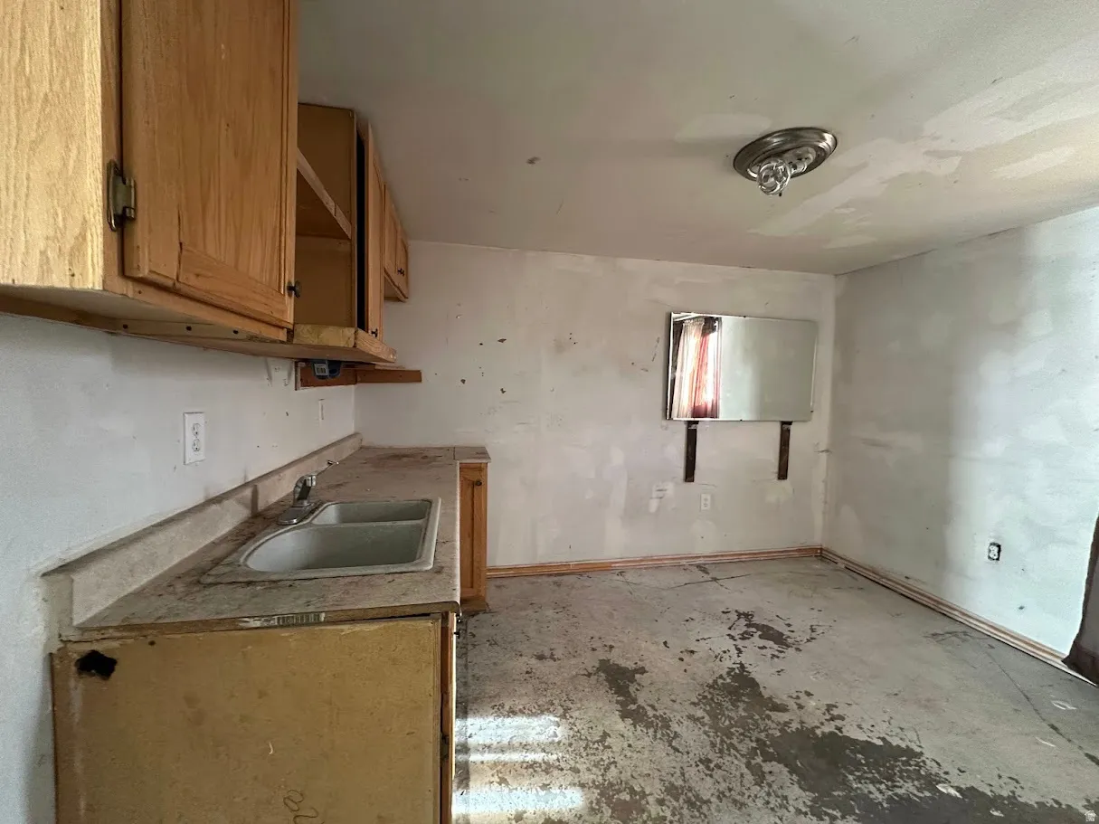 Kitchen area with wood cabinetry, a dual basin sink, and a mounted mirror