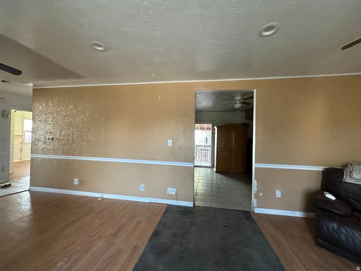 Spacious room featuring partial wood-finish flooring, recessed ceiling lighting, and a textured accent wall with chair rail molding