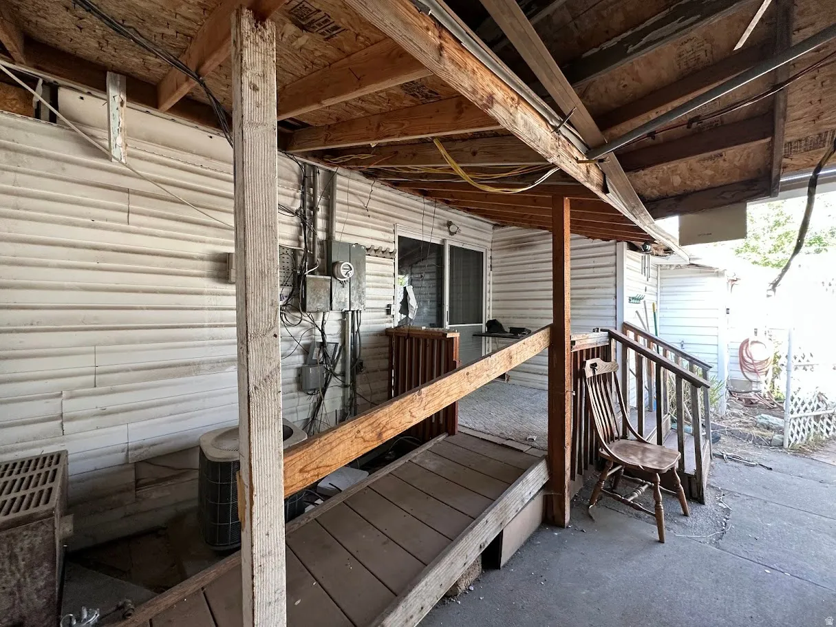 Covered outdoor area featuring a wood-framed overhead structure, a concrete patio, and a wood ramp with railings