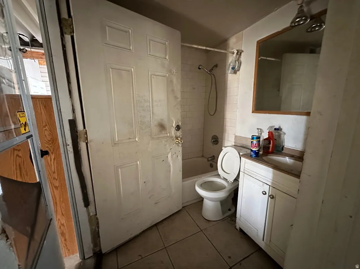 Bathroom featuring a white vanity cabinet, integrated sink, wall-mounted mirror, and a tub with a shower fixture