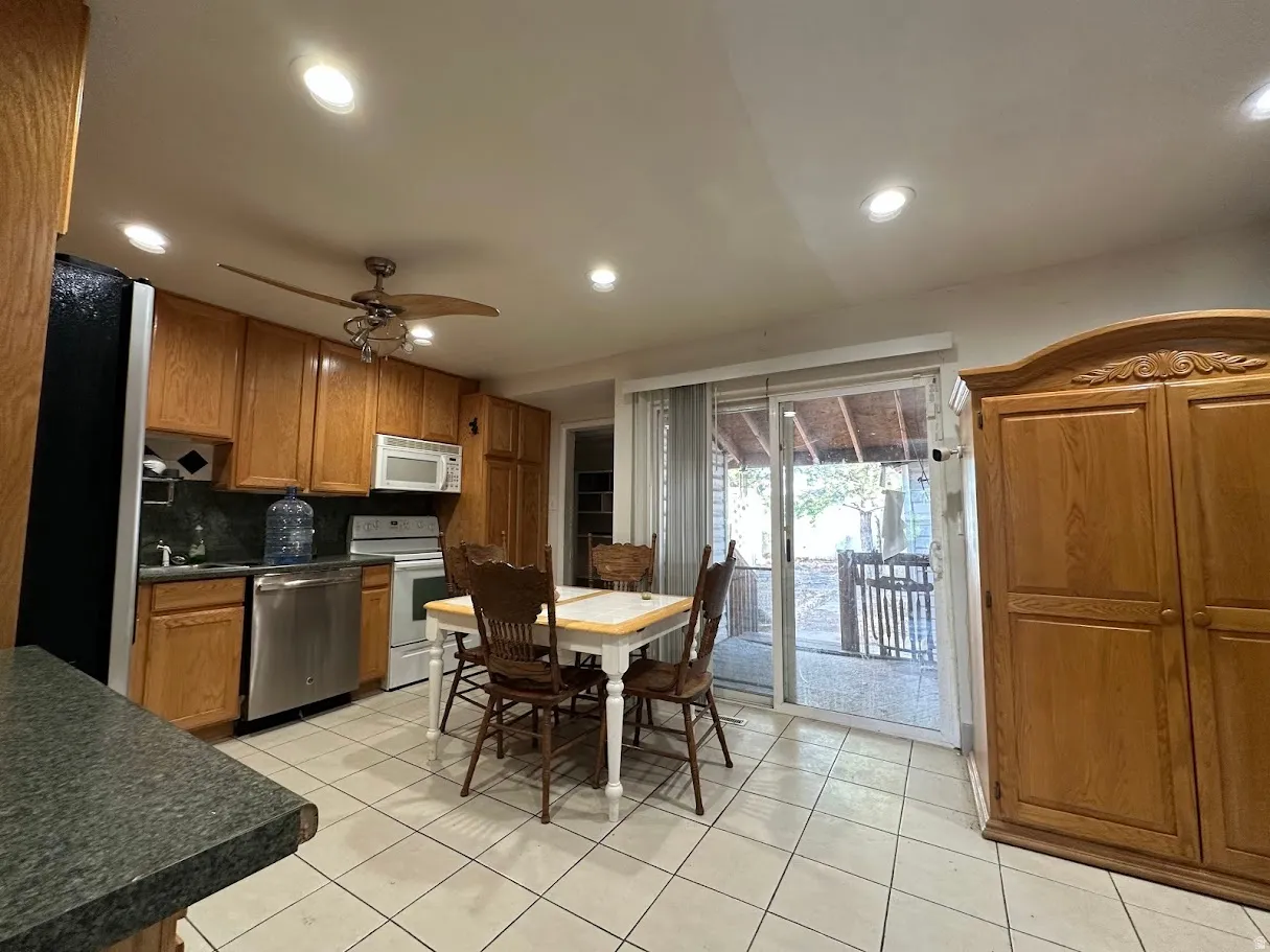 Kitchen featuring wood cabinetry, stainless steel dishwasher, white range with overhead microwave, and recessed lighting