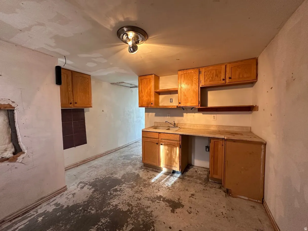 Kitchen area featuring wood-finish cabinetry, a single basin sink, and a multi-light ceiling fixture