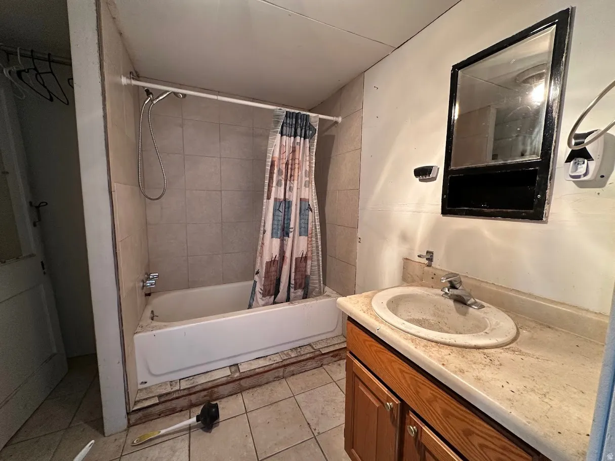 Bathroom featuring a built-in tub with tile surround, a single vanity with an integrated sink, and an overhead mirror