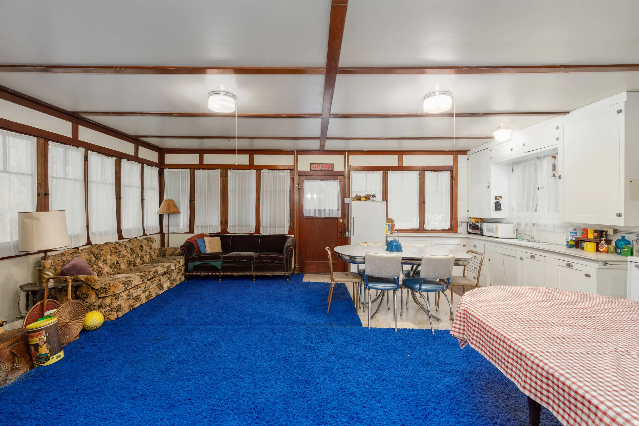 Expansive room featuring a blue carpet, white walls, and exposed wood beams