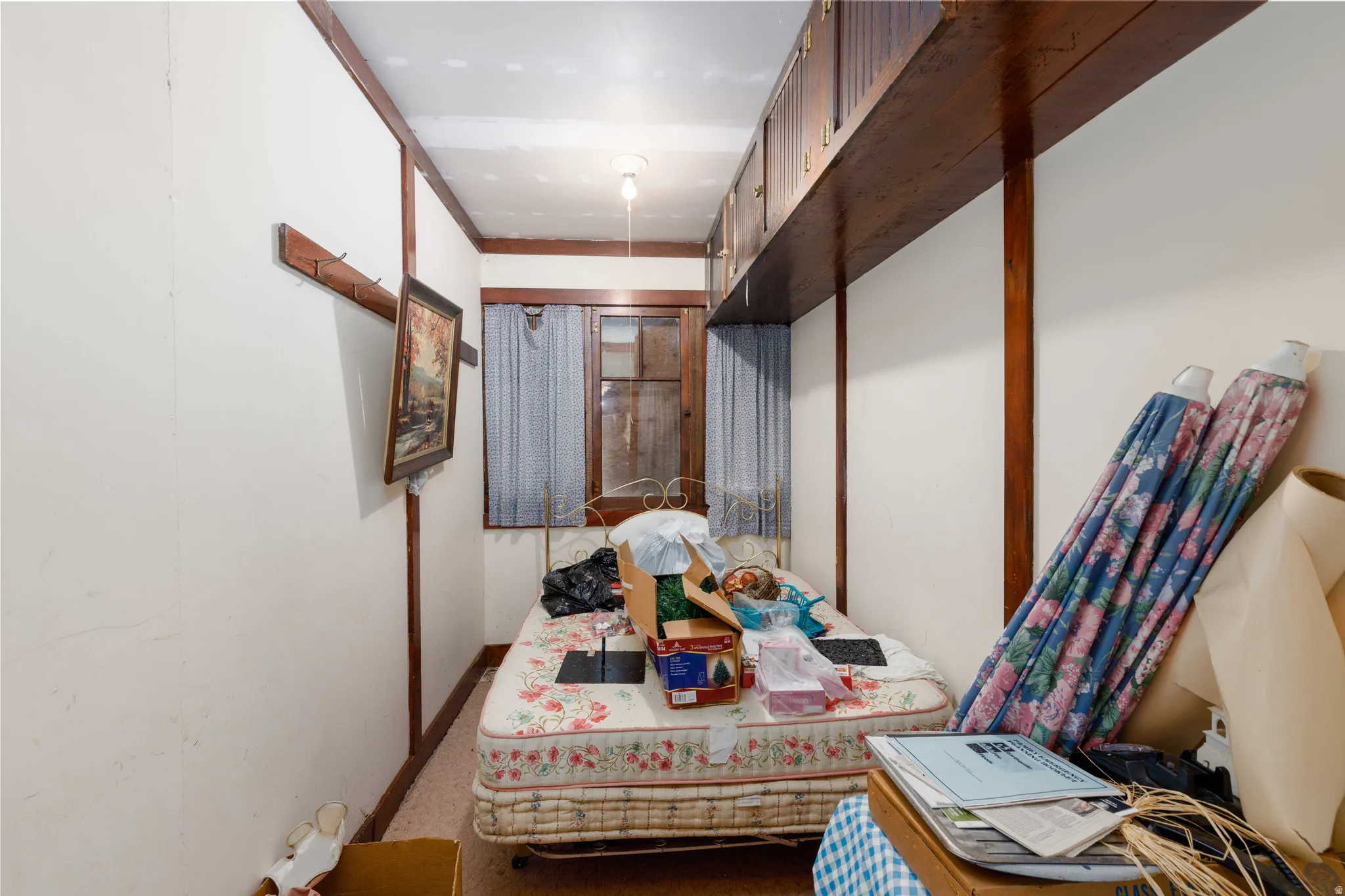 Room featuring wood-finish trim, built-in shelving, and a single window with curtain rods