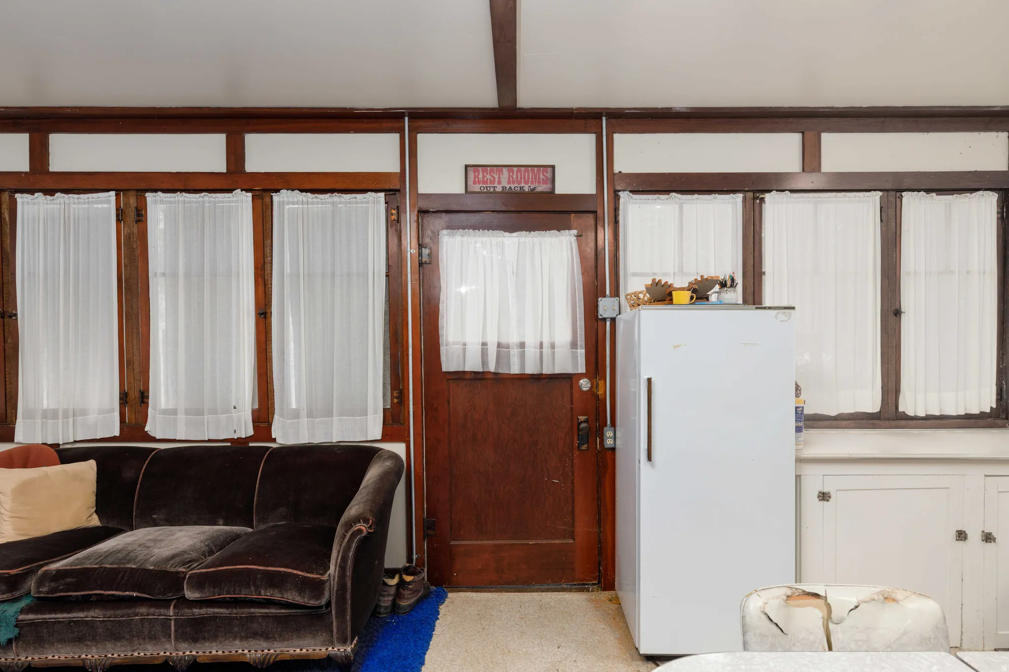 Wood-paneled walls featuring multiple windows with white sheer curtains