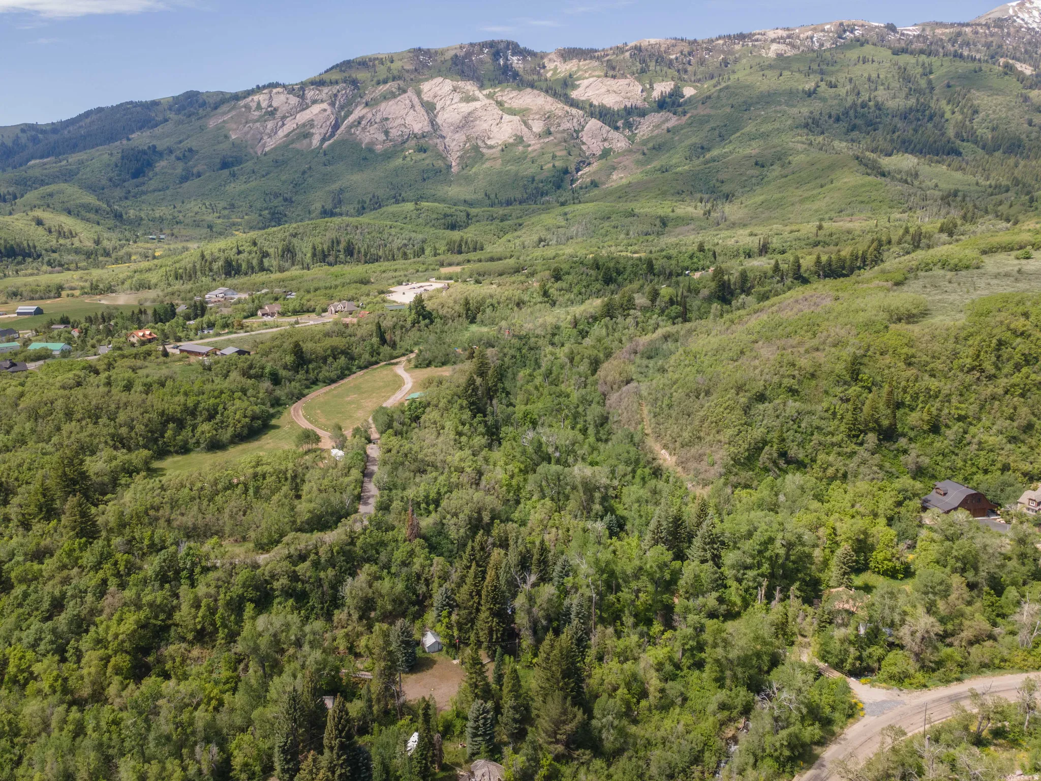 Expansive mountain landscape featuring abundant green foliage and distant rock formations