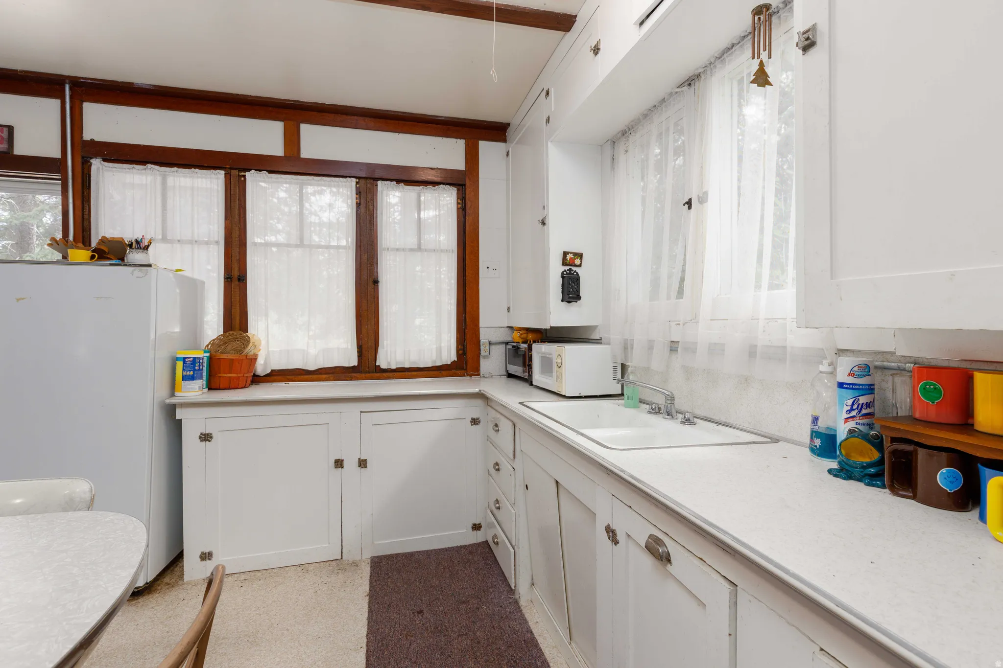 Kitchen featuring white cabinetry with integrated hardware, a built-in sink, and light-toned countertops