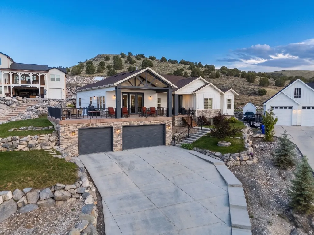 Modern farmhouse exterior featuring white siding, stone accents, and a covered deck