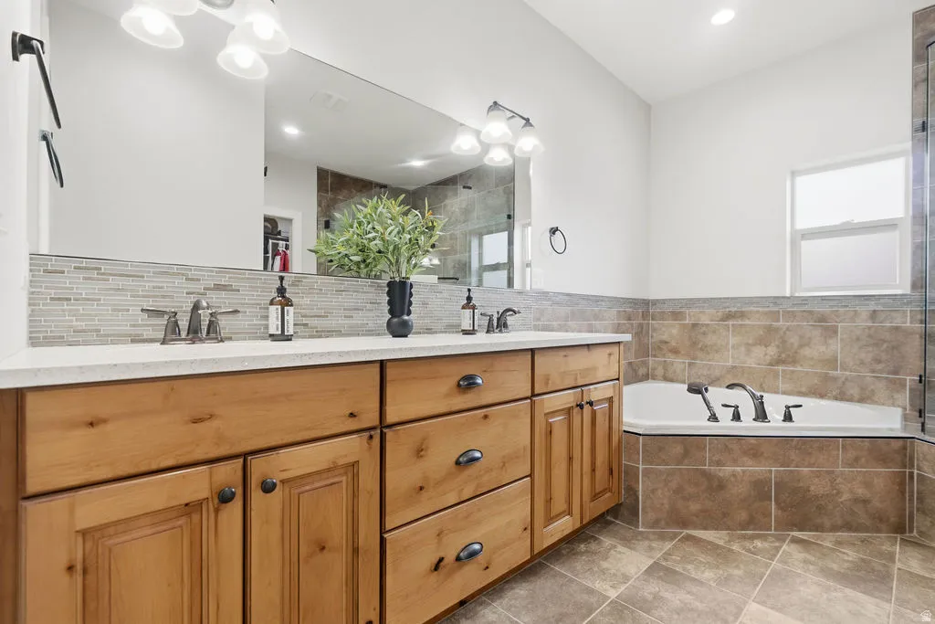 Double vanity with light wood cabinetry and stone-look countertop