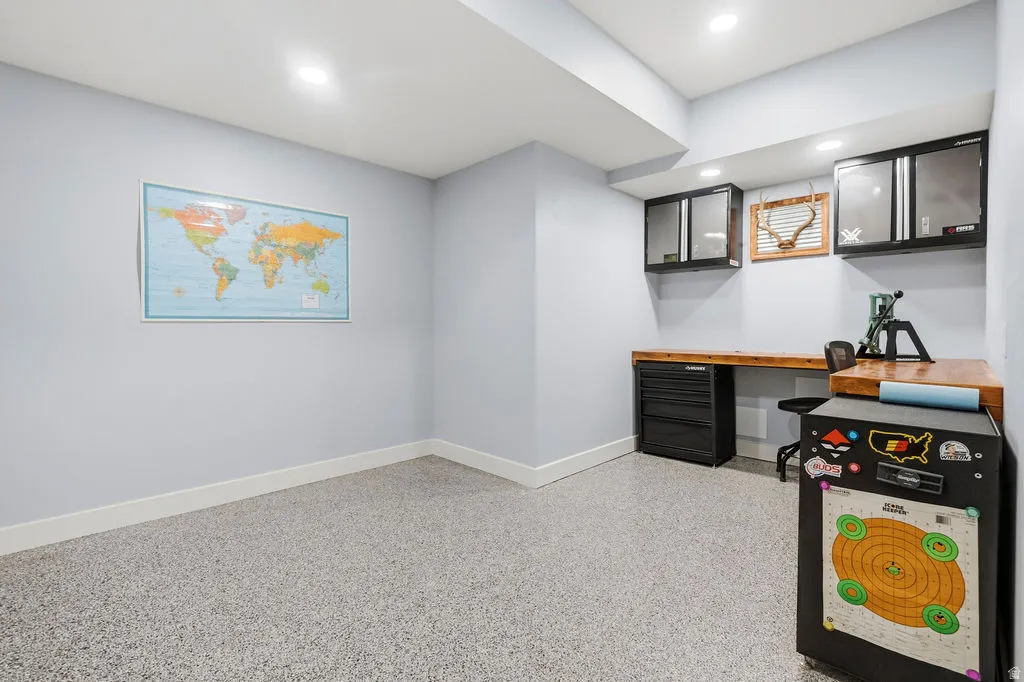 Versatile room featuring epoxy flooring, recessed lighting, a built-in wood-finish countertop, and wall-mounted cabinetry