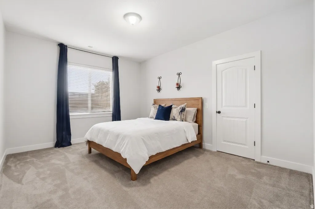 Carpeted room with a double-pane window, white trim throughout, and a paneled interior door with black hardware