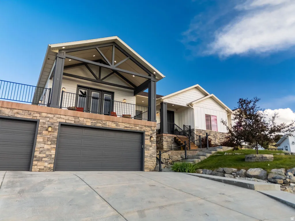 Multi-level residence featuring a stone-clad lower level with a two-car garage and a concrete driveway