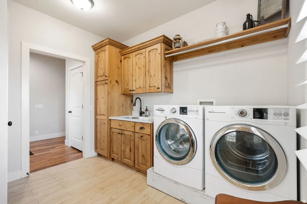 Dedicated laundry room featuring light wood-finish cabinetry, a single basin sink with a black gooseneck faucet, a white countertop, and tile flooring