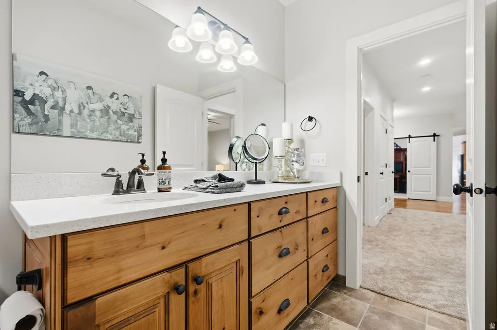 Bathroom vanity featuring a light wood-finish cabinetry, a white countertop, and a single undermount sink with a two-handle faucet