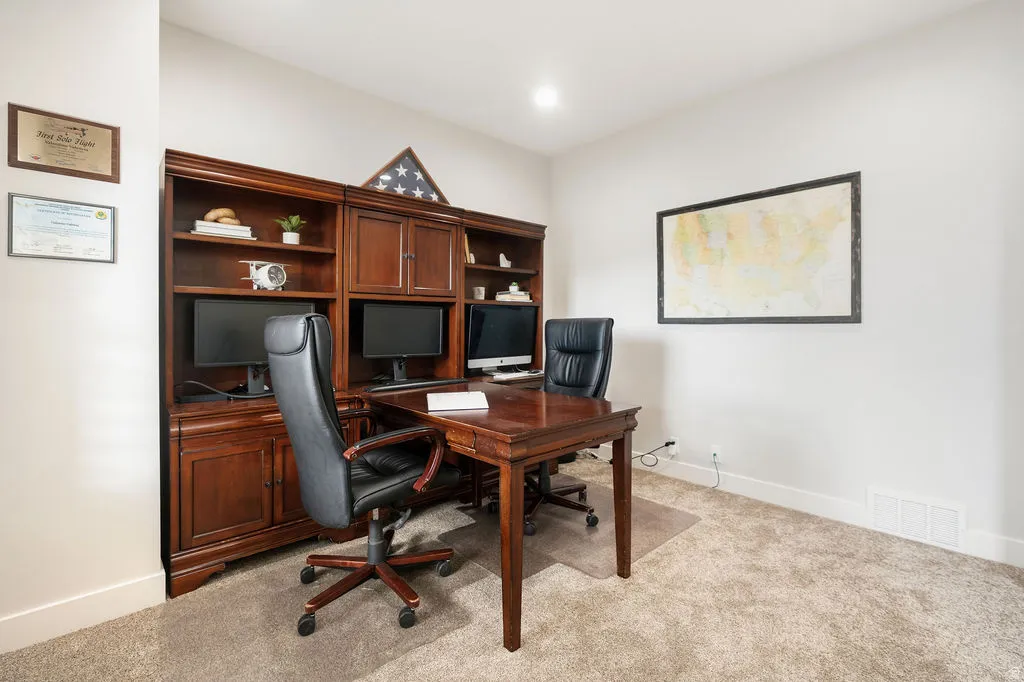 Dedicated office space featuring built-in wood-finish cabinetry with shelving and enclosed storage