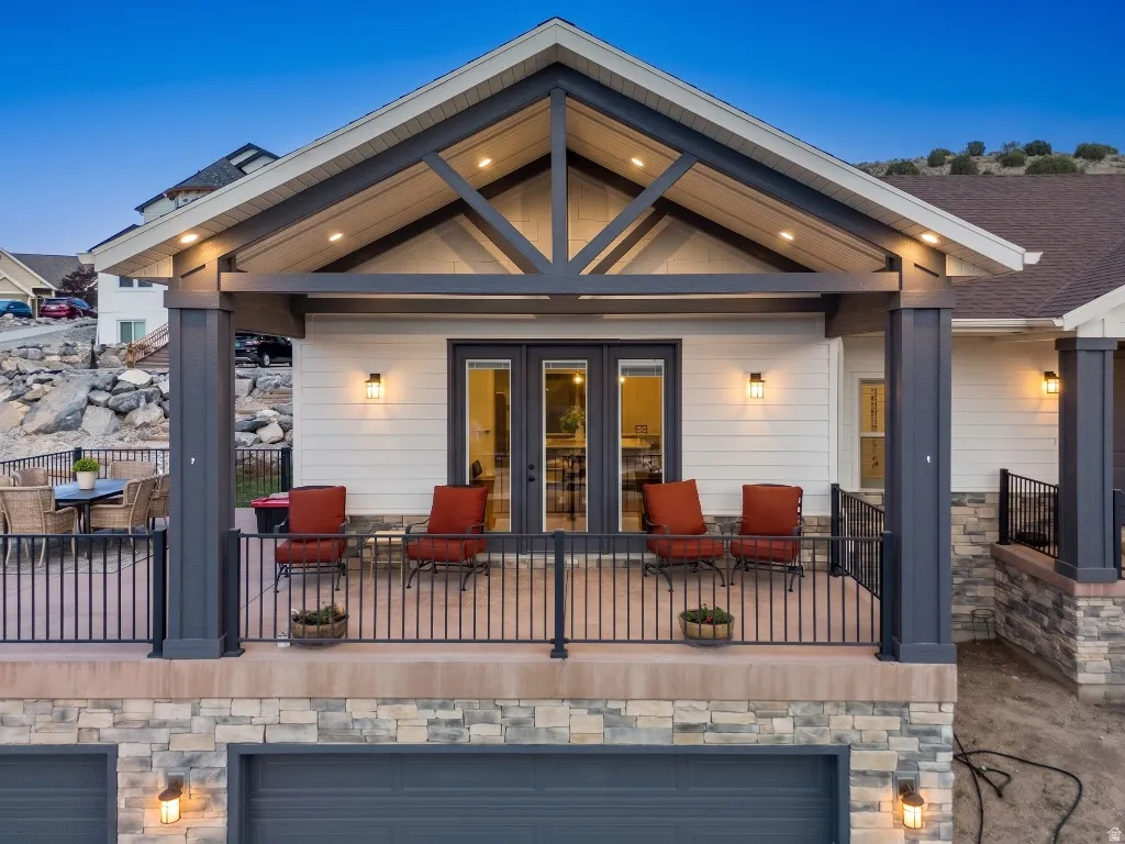 Covered outdoor patio featuring exposed beam gable roof, recessed lighting, and double-door entry