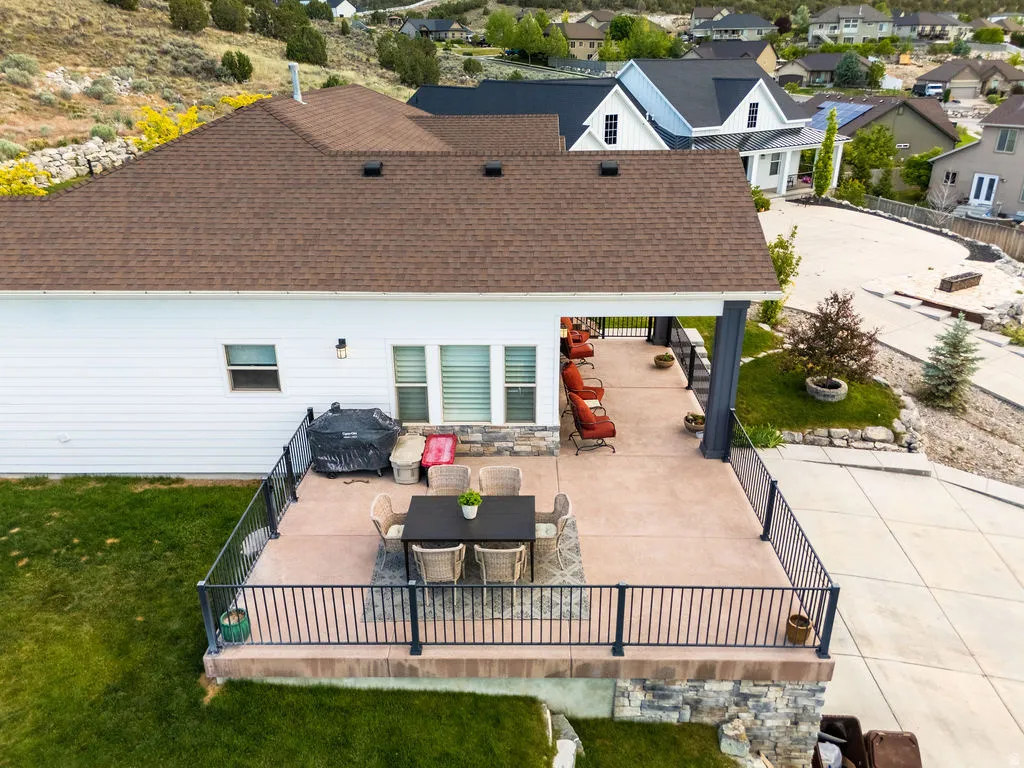 Expansive patio featuring a concrete surface, black metal railings, and a partial roof cover