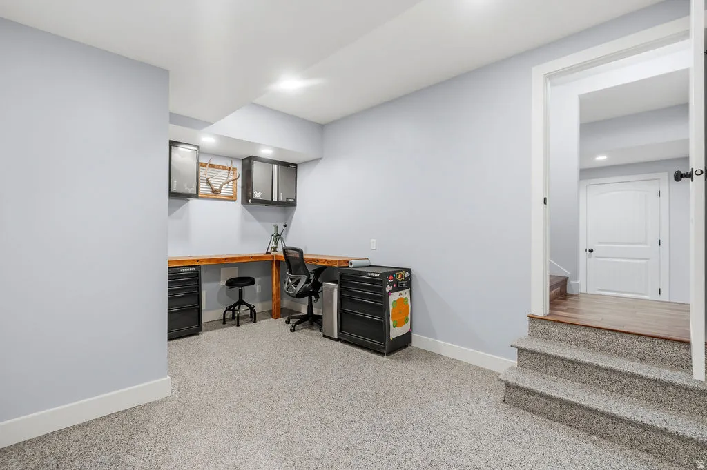 Finished lower level featuring light gray walls, white trim, and light-colored flecked carpeting