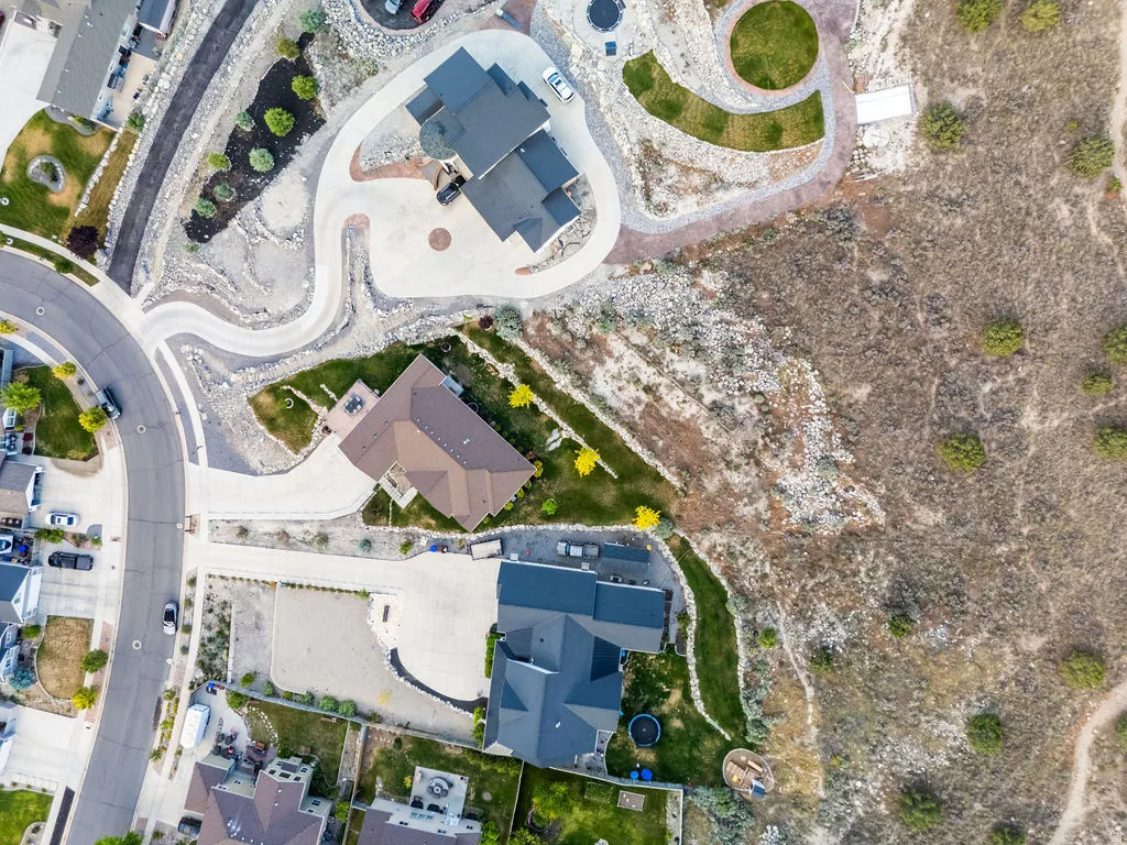 Aerial representation of residential properties featuring a paved street, extensive driveway surfaces, and a variety of architectural rooflines