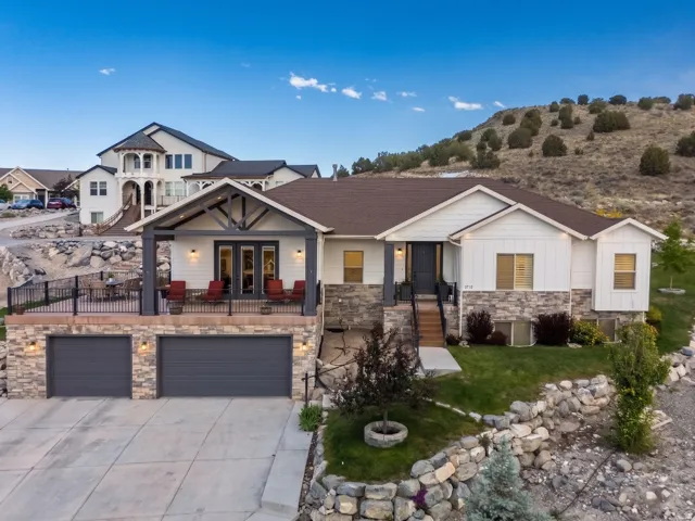 Contemporary residence featuring white siding, stone accents, and a dark brown roof