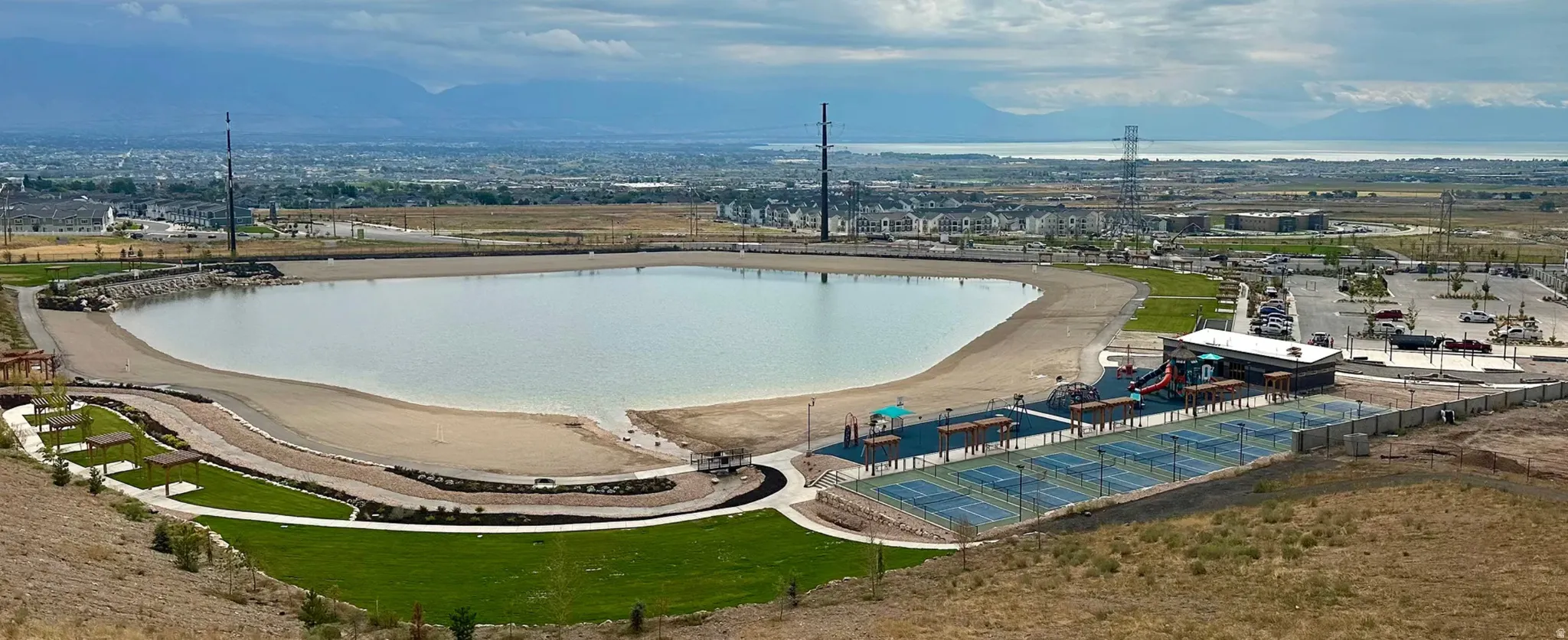 Expansive recreational lake with sandy shores, surrounded by manicured green spaces