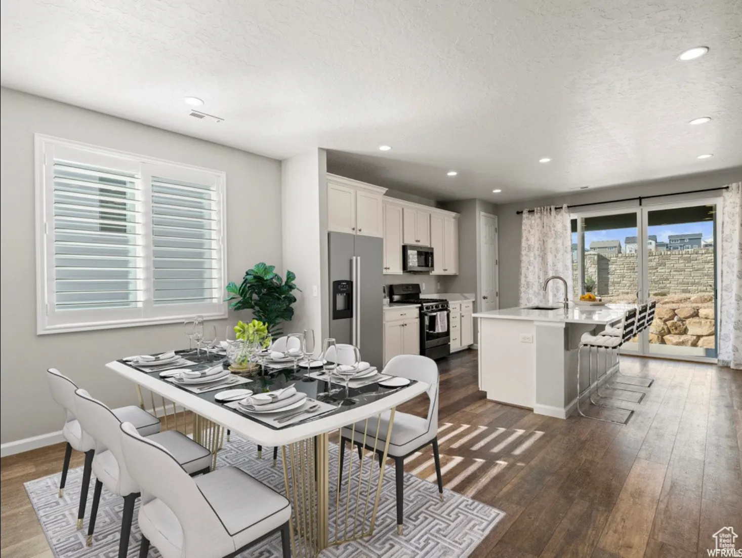 Open-concept living space featuring wood-finish flooring, recessed lighting, and a window with plantation shutters