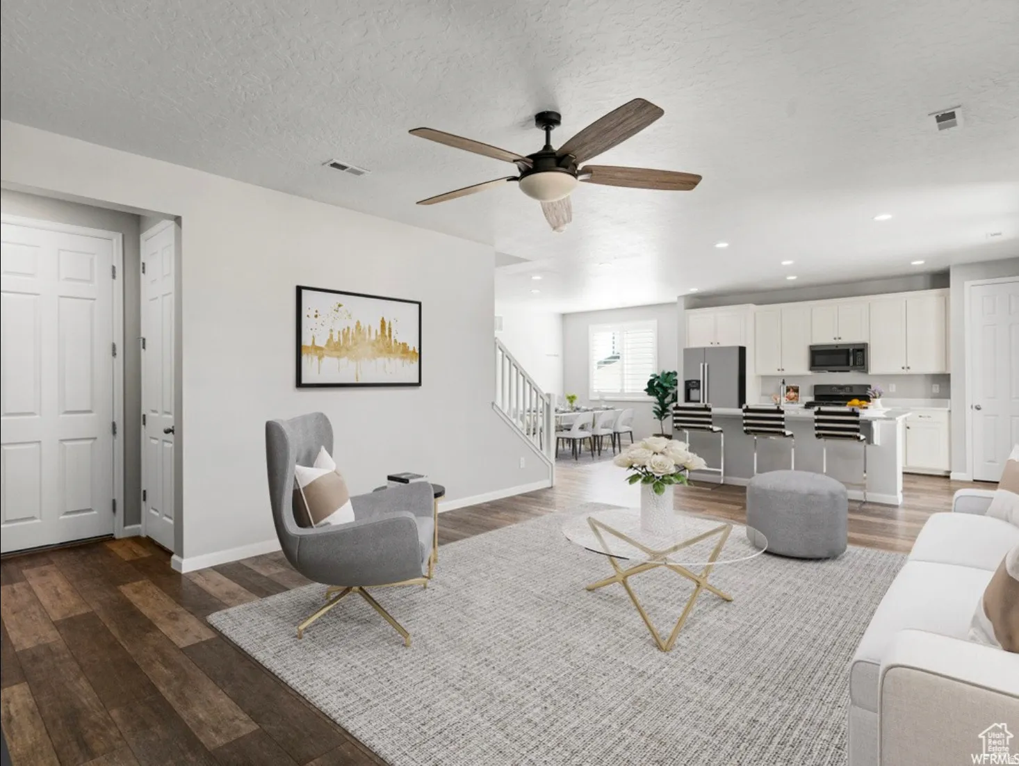 Open-concept living area featuring wood-finish flooring, a ceiling fan with integrated lighting, and recessed ceiling lights
