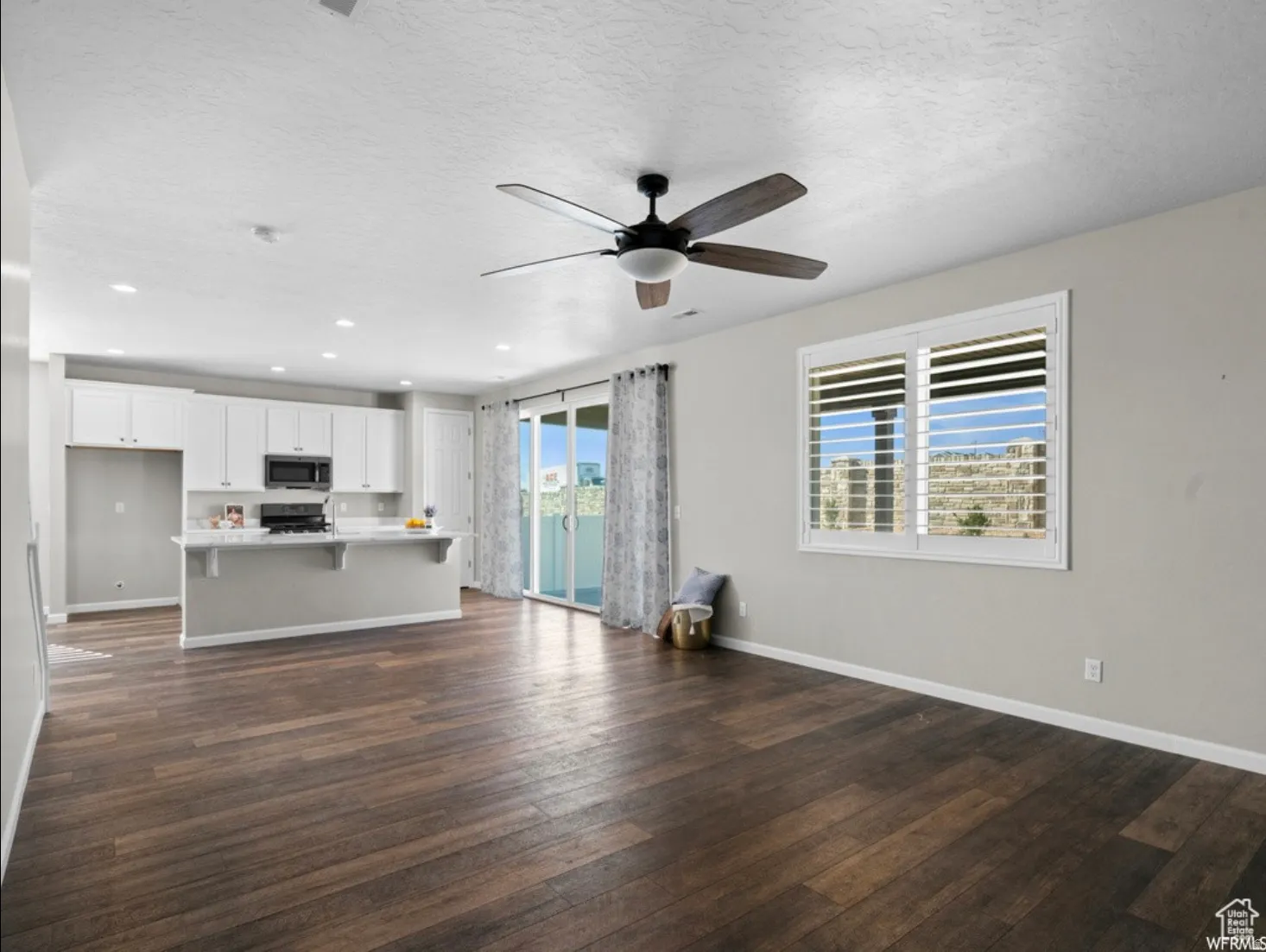 Open-concept living space featuring wood-finish flooring, a contemporary ceiling fan, and recessed lighting