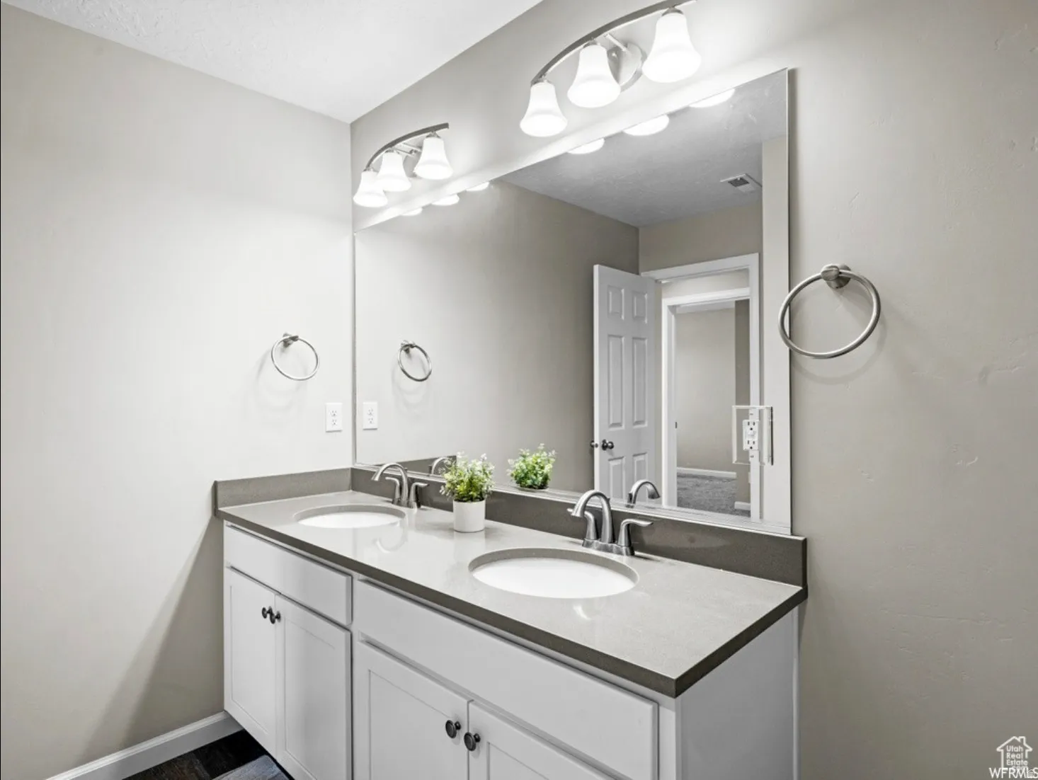 Dual vanity with undermount sinks, stone countertop, brushed nickel fixtures, and white cabinetry