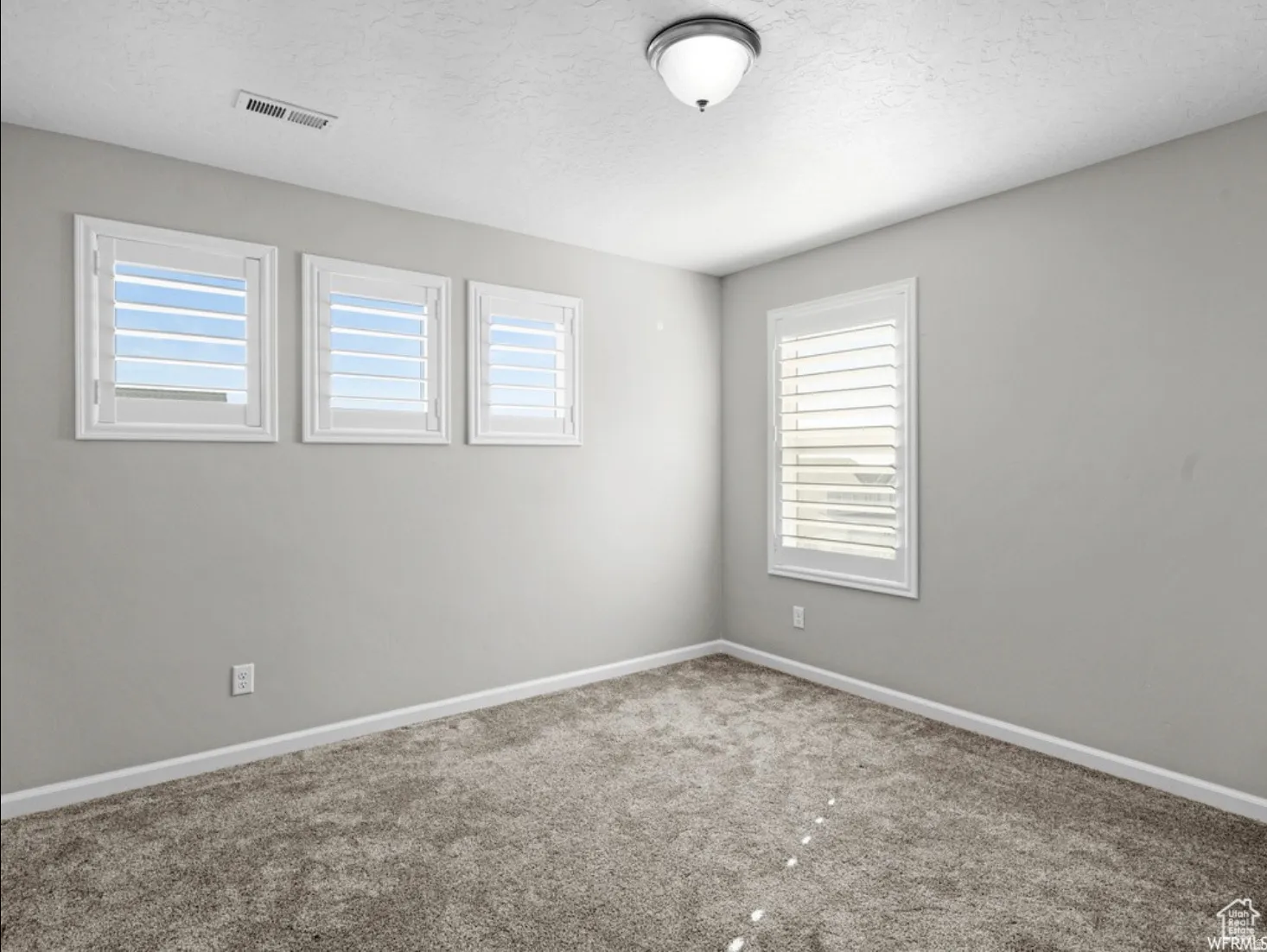 Neutral gray walls frame a room featuring plush gray carpeting