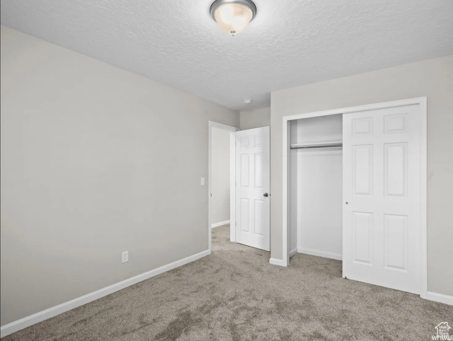 Light gray wall paint with white trim, gray carpet flooring, and a semi-flush mount ceiling light
