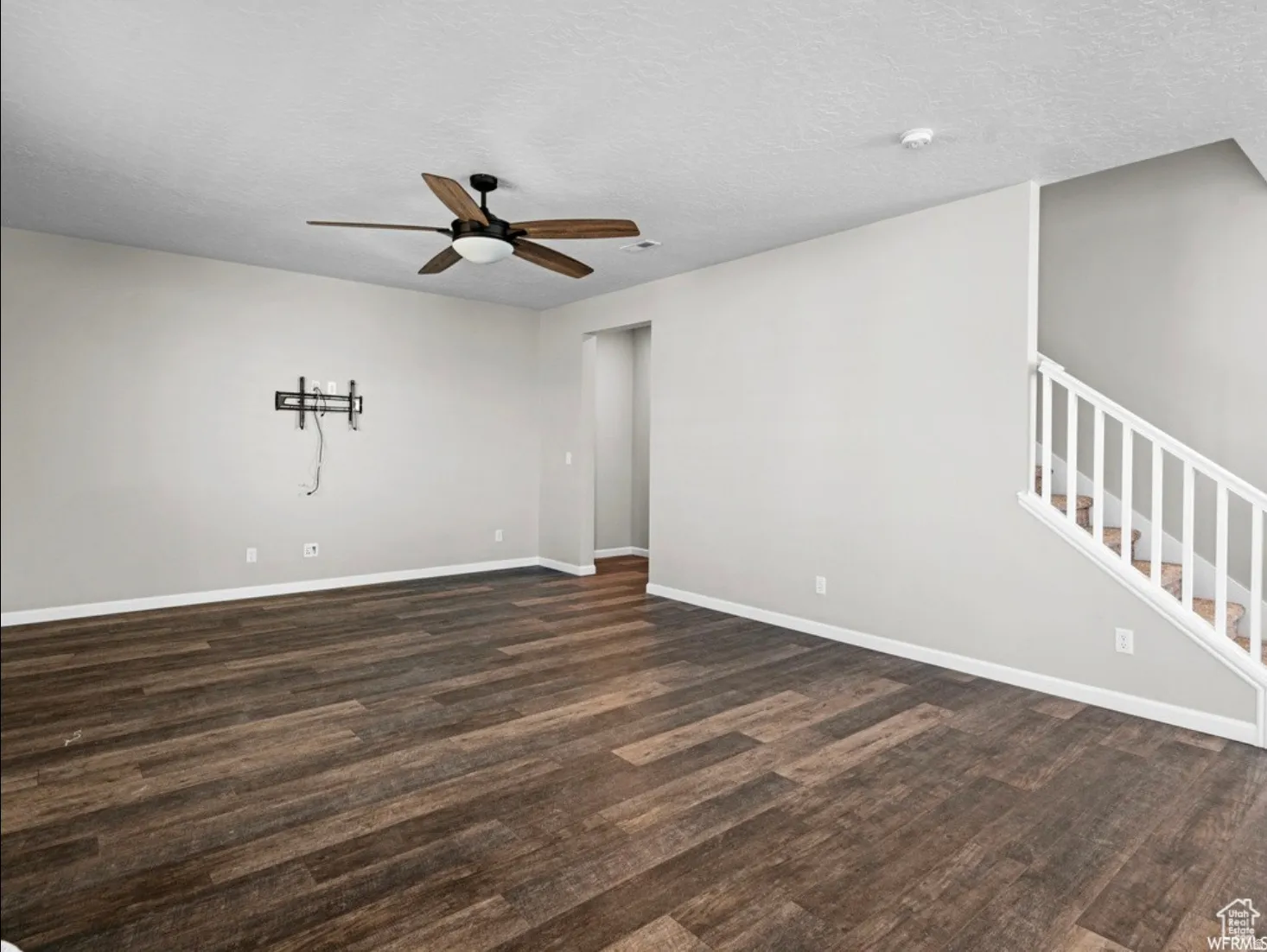 Spacious interior featuring wood-finish flooring, a contemporary ceiling fan, and light gray wall paint