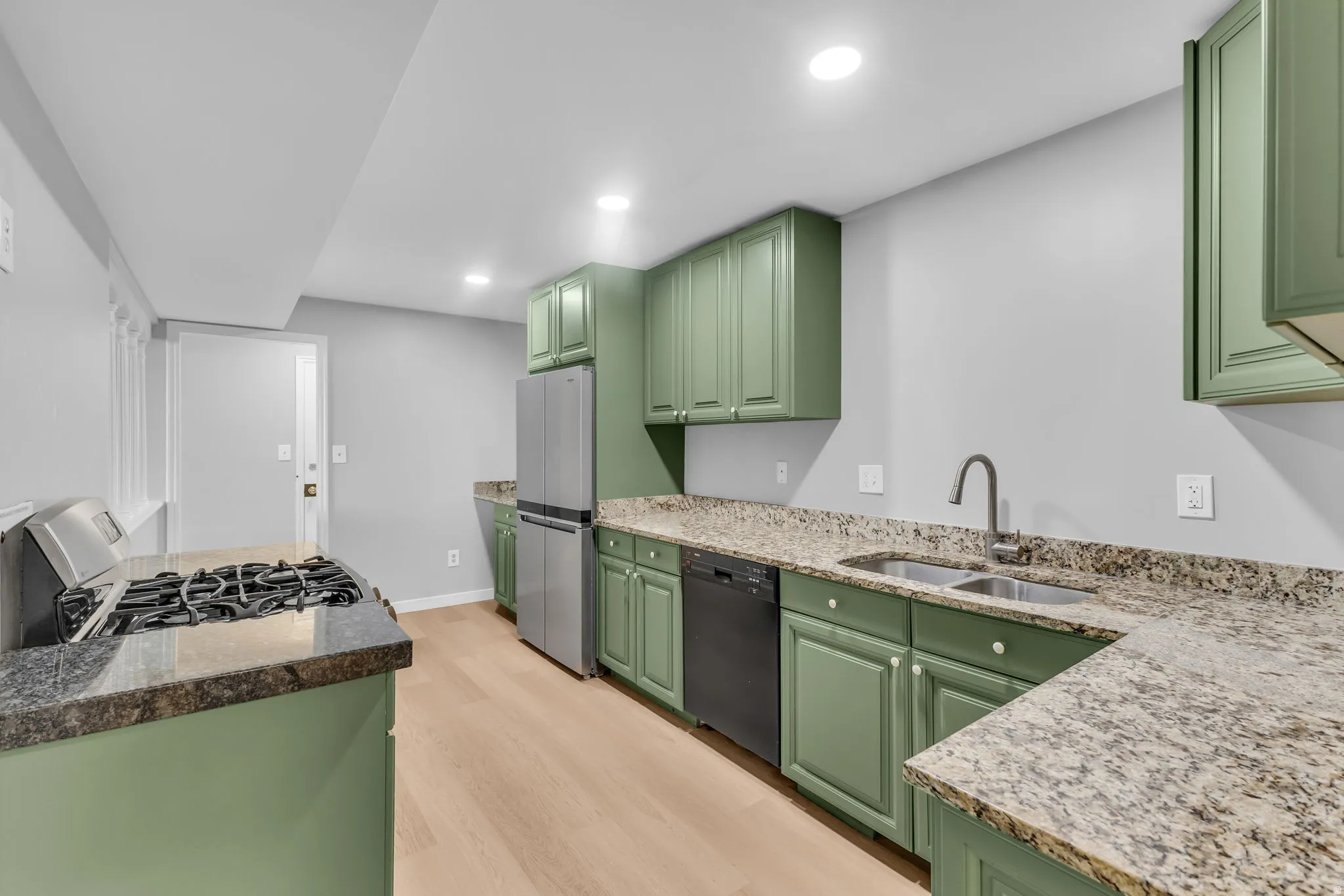 Kitchen featuring green cabinetry, light-toned wood-finish flooring, recessed lighting, and granite countertops