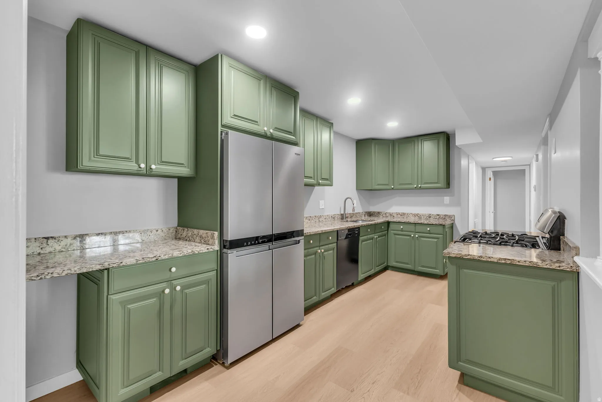 Kitchen featuring sage green cabinetry, stone countertops, stainless steel refrigerator, stainless steel dishwasher, and a gas range