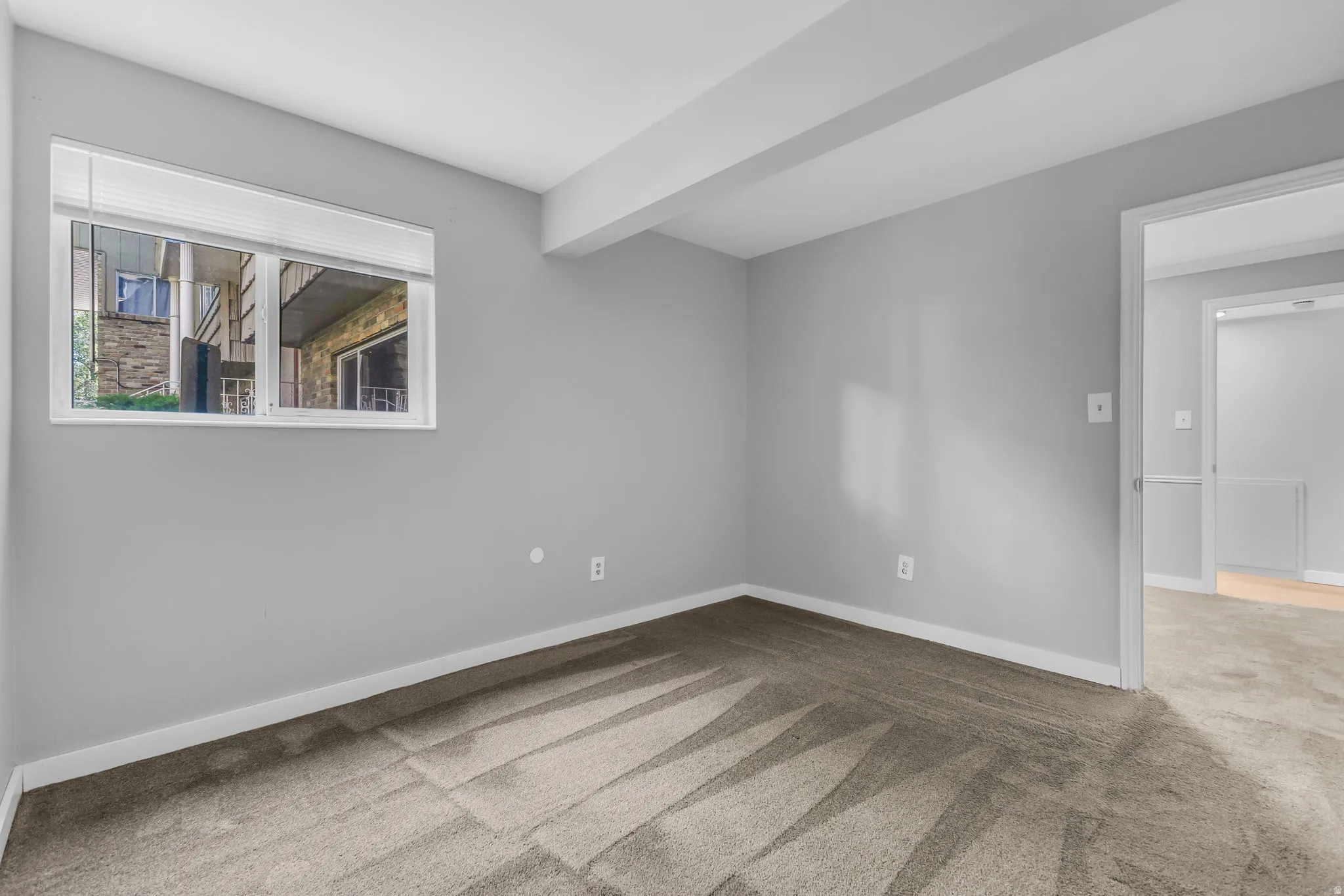 Carpeted room with a window featuring white blinds