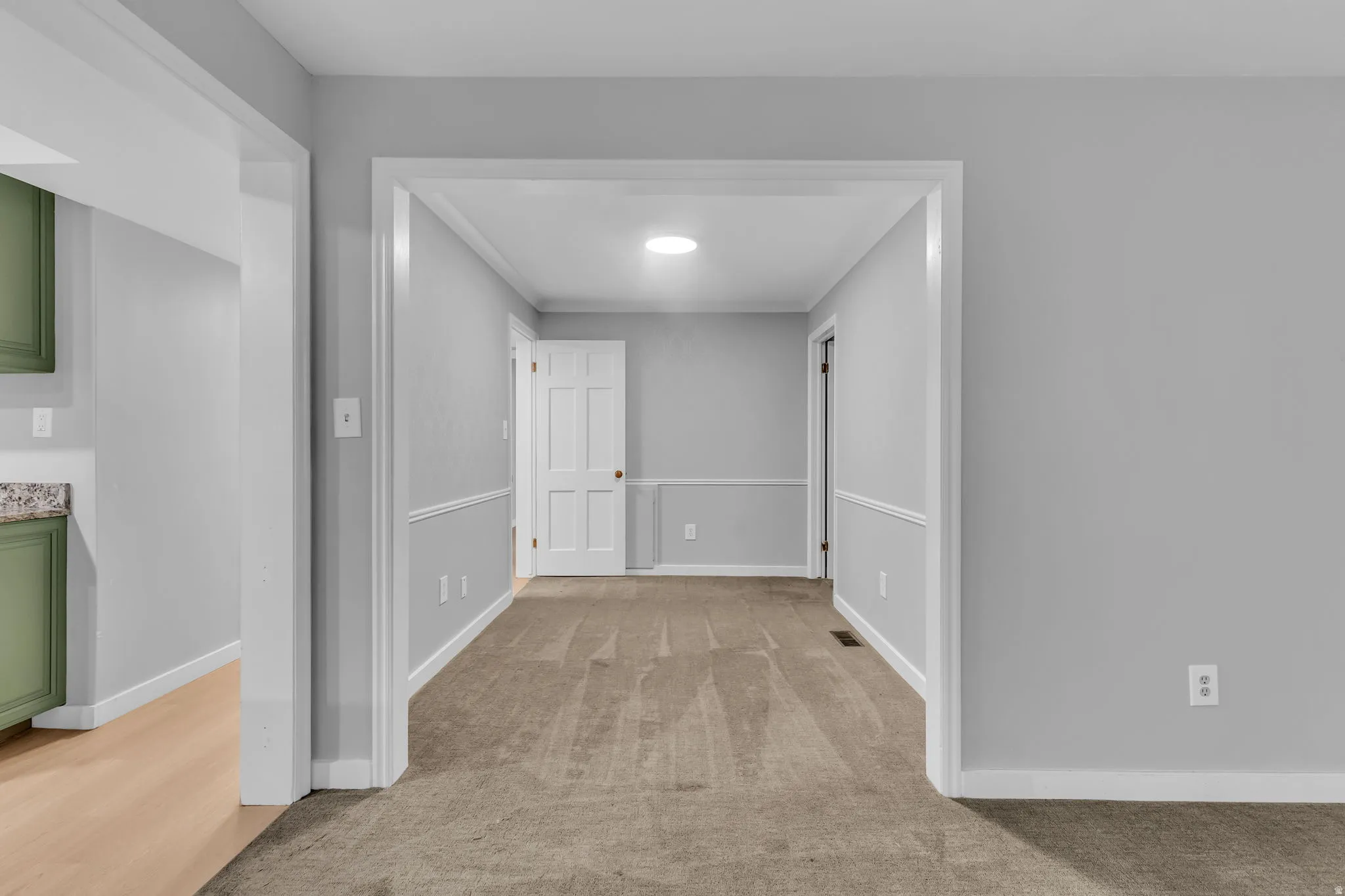Carpeted room with light grey walls and white wainscoting