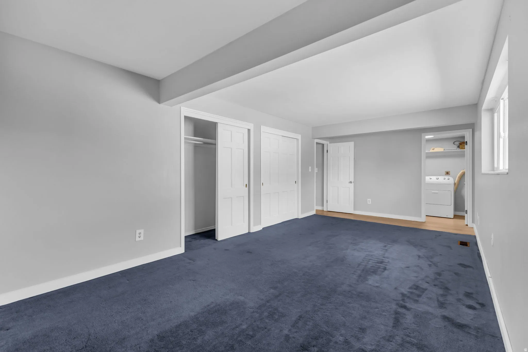 Spacious room featuring plush blue carpeting, light gray walls, and white trim