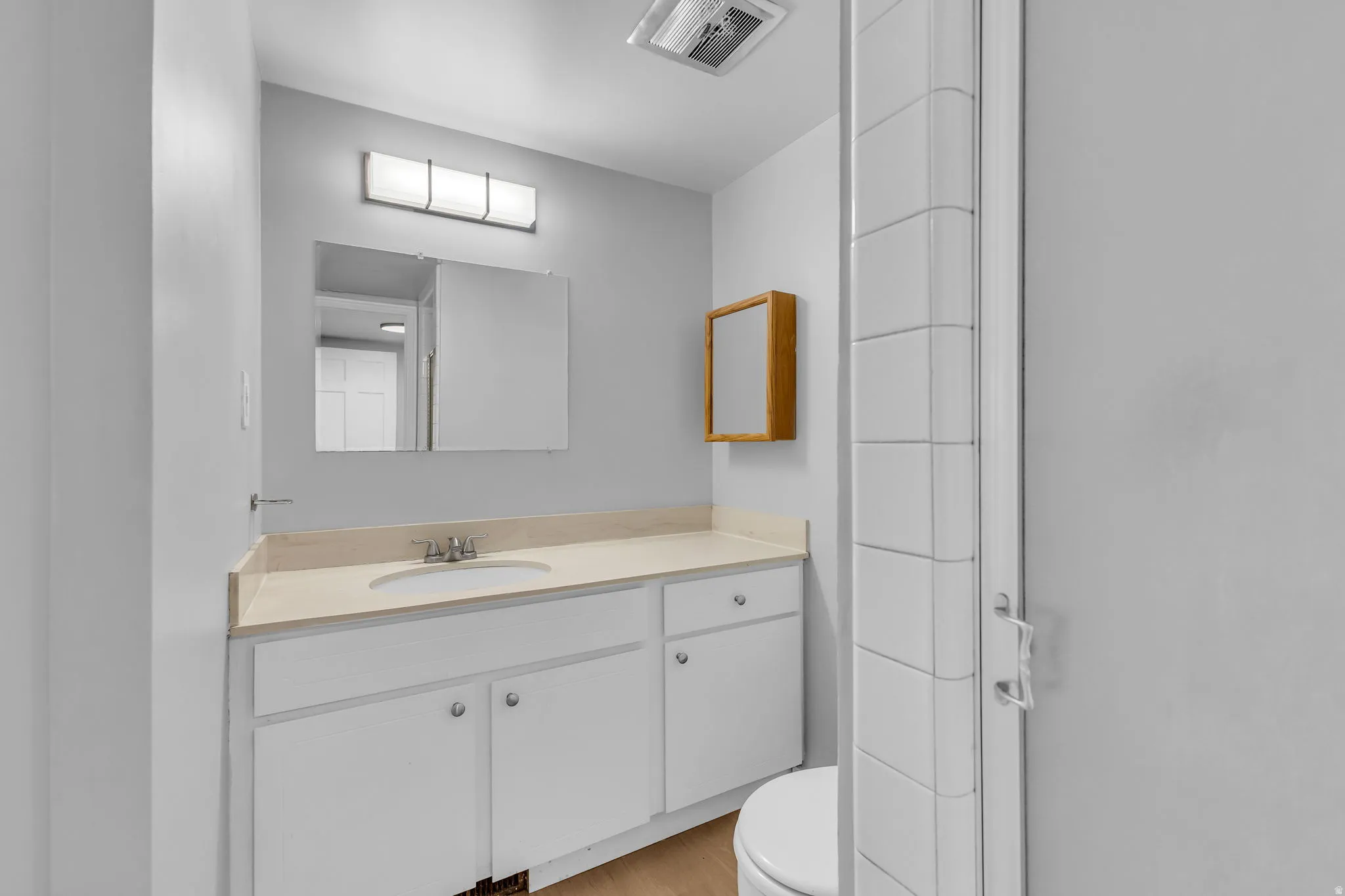 Vanity with integrated sink, light-toned countertop, and white cabinetry