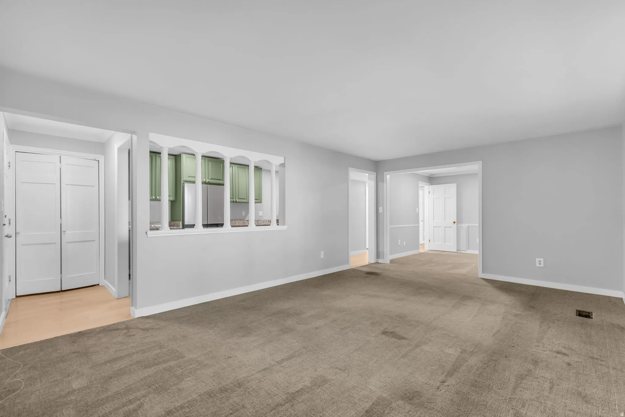 Spacious living area featuring neutral carpeting, light gray walls, and white trim