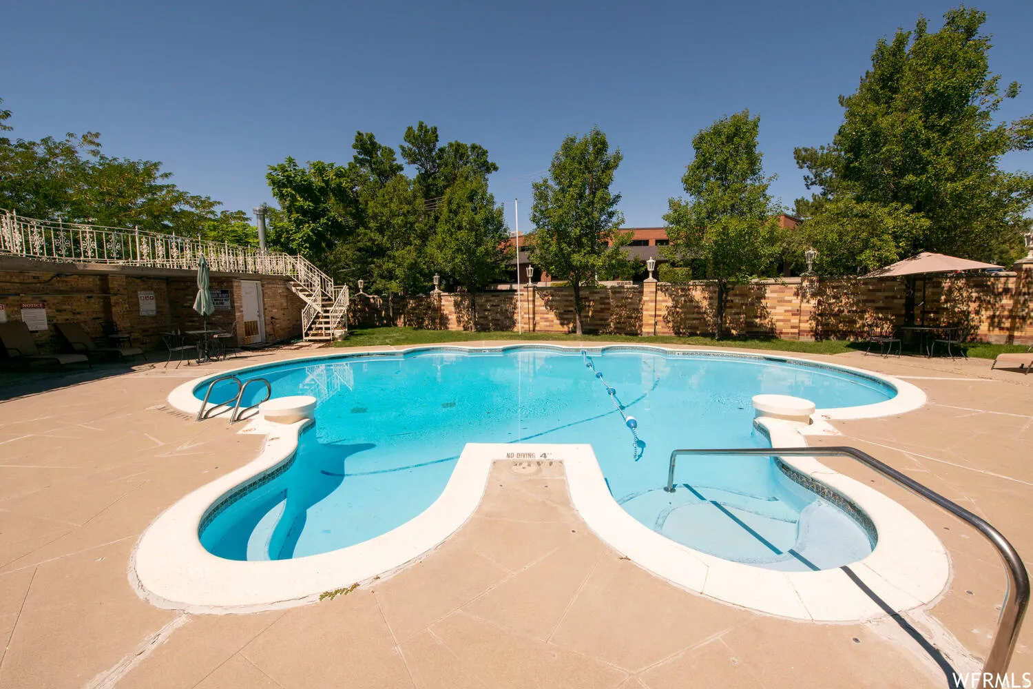 Kidney-shaped swimming pool with integrated spa and concrete surround