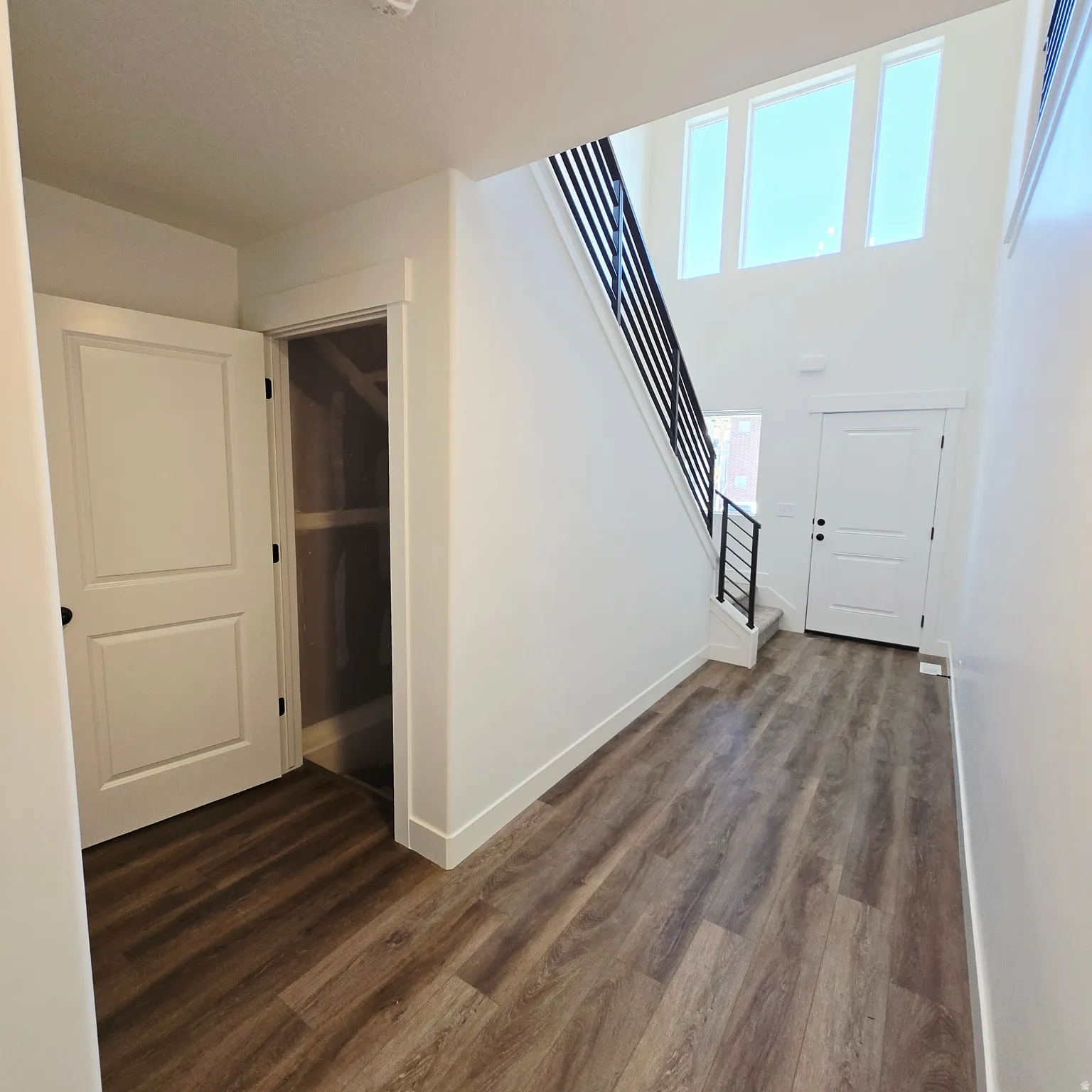 Entryway featuring wood-finish flooring and a staircase with a black metal railing