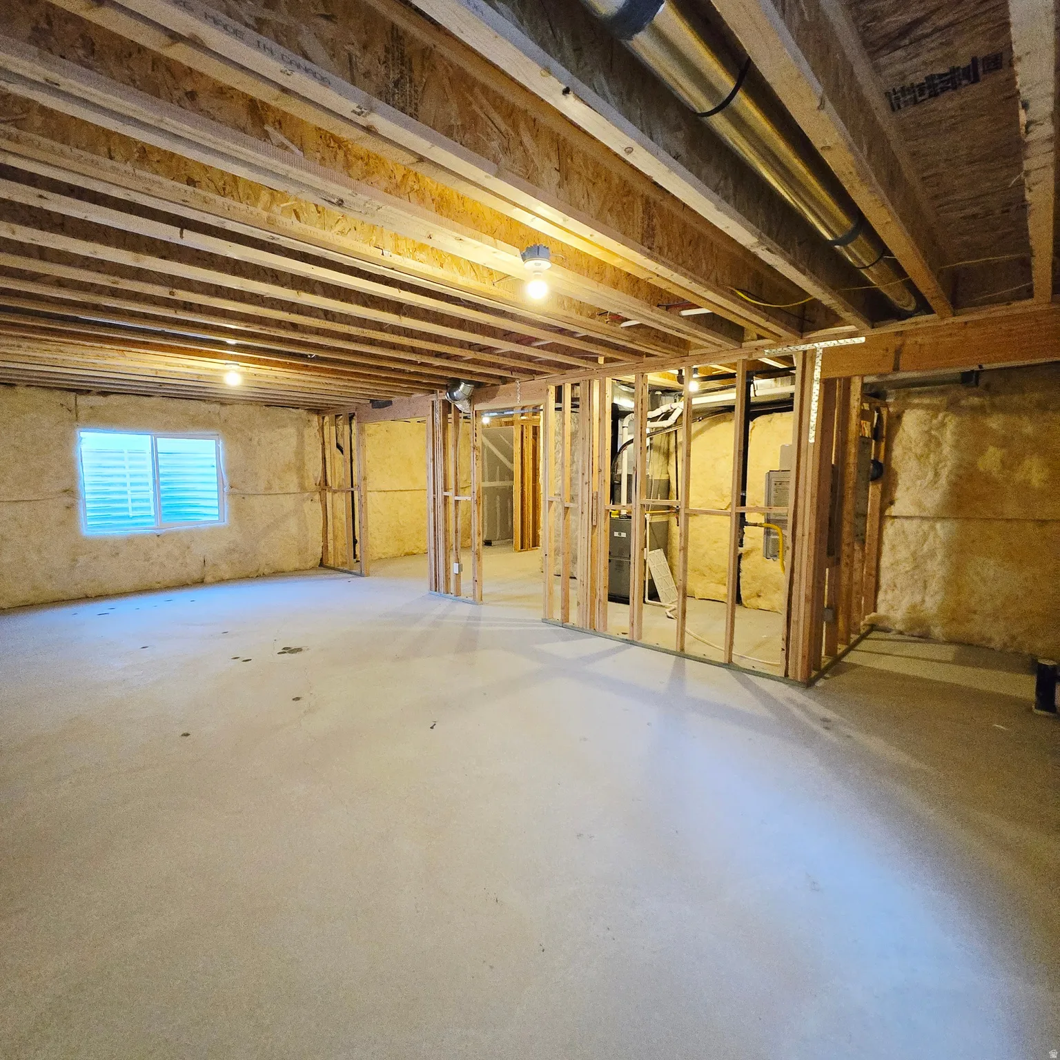 Unfinished basement featuring exposed wood joists and subflooring, framed wall studs, and concrete flooring