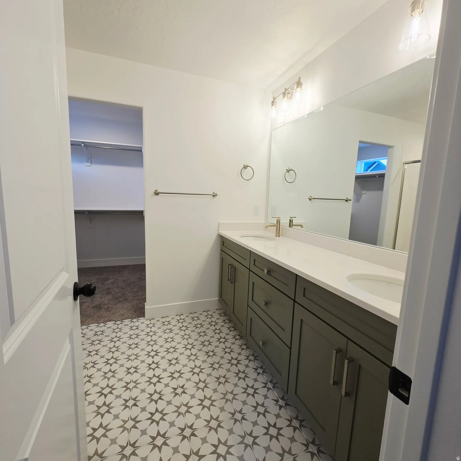 Bathroom featuring a dual vanity with a light countertop, gray cabinetry, and brass-finish fixtures